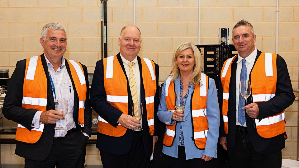 4 people in suits and high visibility vests holding wine glasses
